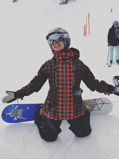 A snowboarder kneeling while posing for a photo